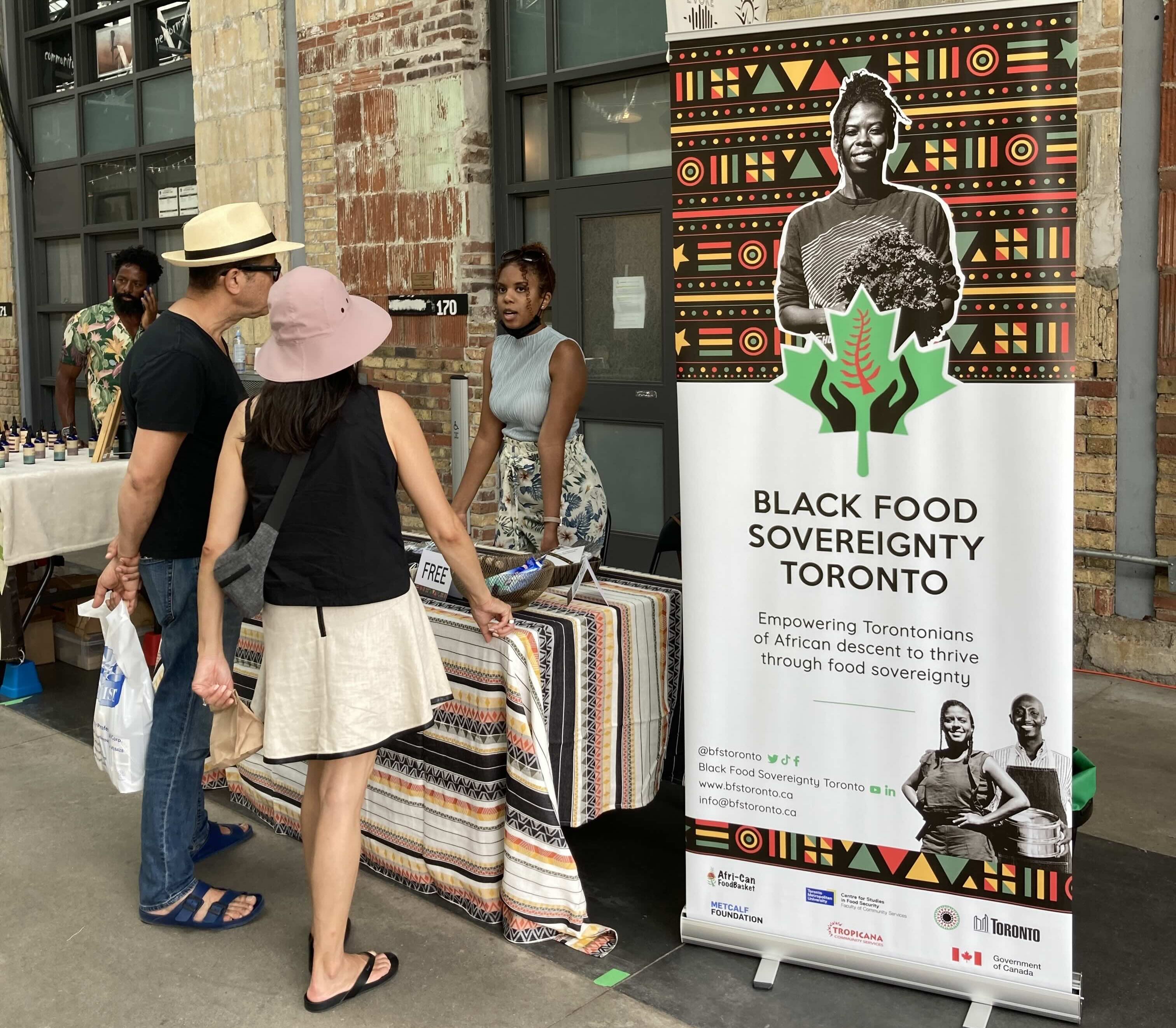 People talking at a market stand to learn more about Black Food Sovereinty Toronto 